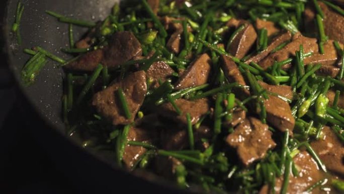 有人在平底锅上煎猪肝和韭菜。用韭菜炒猪肝。亚洲食物菜单。泰国菜。