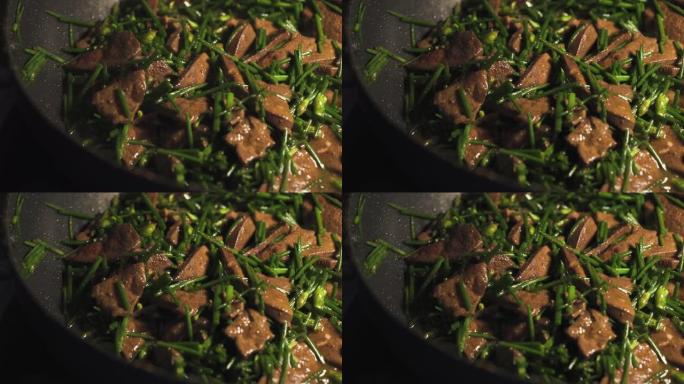 有人在平底锅上煎猪肝和韭菜。用韭菜炒猪肝。亚洲食物菜单。泰国菜。