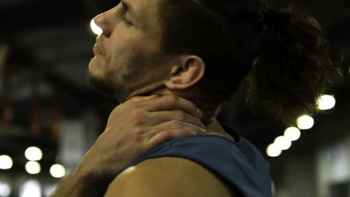 男性运动员在筋疲力尽的锻炼后摩擦紧张的脖子和肩膀，特写镜头