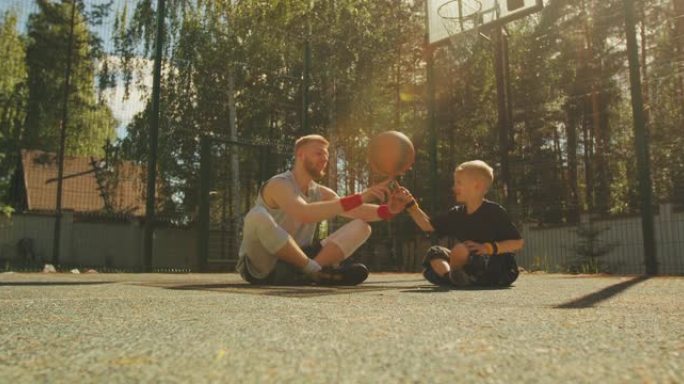 专业篮球运动员教练在户外球场上的运动小男孩的手指上给旋转球