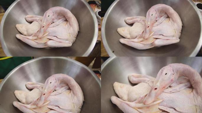 整只生鸭准备在不锈钢碗中烹饪，整只鸭新鲜生放在托盘上，没有现成的配料和香料特写