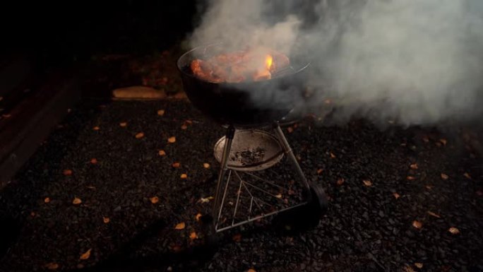 食物在黑色圆形烤架上煮熟，冒烟并出现火焰