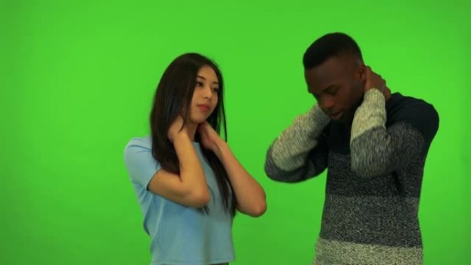 一个年轻的亚洲妇女和一个年轻的黑人男子拉伸-绿色屏幕工作室