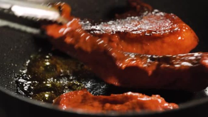 红色生猪肉在黑锅上烤。厨师翻转。美味。有些烧焦了。宏观特写镜头。
