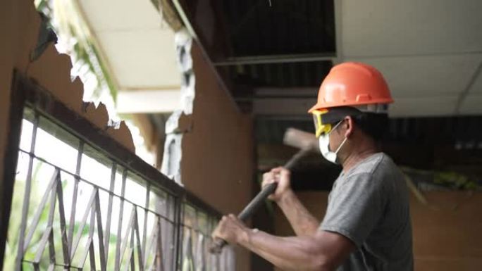 建筑工人戴防护面罩用大锤拆墙