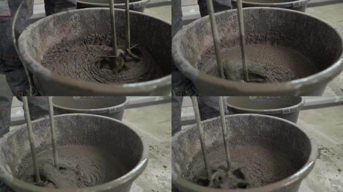砂浆在桶中混合。地板维修。建筑地面砂浆的混合。在斗式搅拌机中搅拌水泥，在侧面工作时使用抹刀，施工