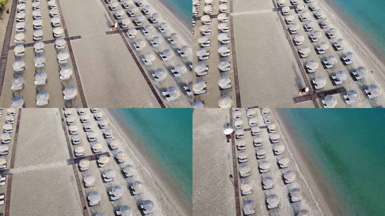 在沙滩上安排豪华海滩酒吧和带草伞的日光浴躺椅。鸟瞰图