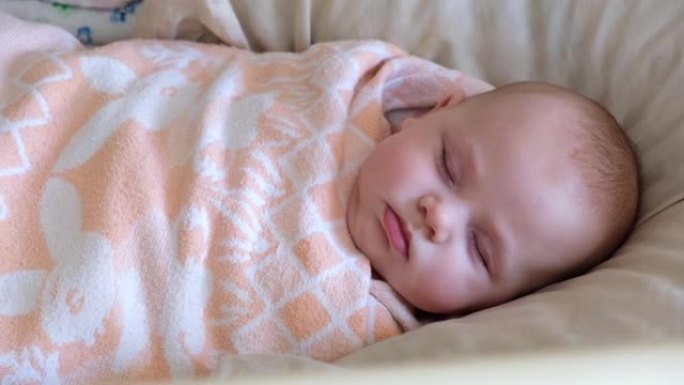 棉襁褓中的婴儿安全睡眠环境。特写。可爱的新生婴儿睡在床上。新生儿在婴儿床里小睡。婴儿襁褓。包裹在温暖