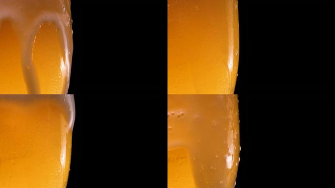 淡啤酒正在倒入玻璃杯中。装有水滴的冰镇啤酒。啤酒形成泡沫特写。新鲜和泡沫。孤立的黑色背景。