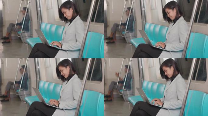 女商人坐在地铁上使用笔记本电脑工作