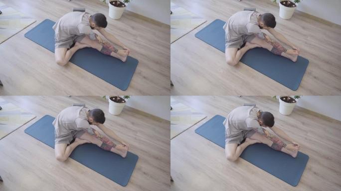 男人练习瑜伽，左腿握着脚趾。在家进行伸展运动