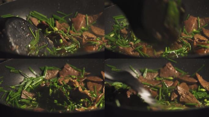 有人在平底锅上煎猪肝和韭菜。放入棕色沙司。用韭菜炒猪肝。亚洲食物菜单。泰国菜。