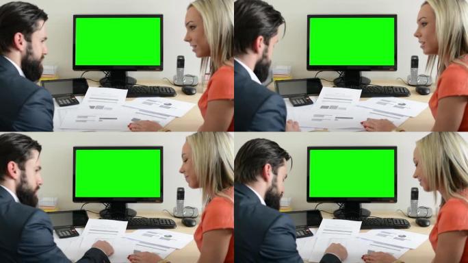 女人和男人在办公室谈文档-台式电脑绿屏
