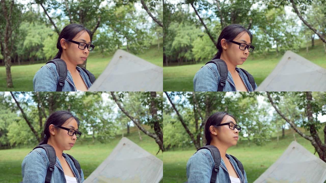 一位女游客，背着背包在户外放松，在森林里的地图上寻找正确的方向。度假概念上的旅行和生活方式。