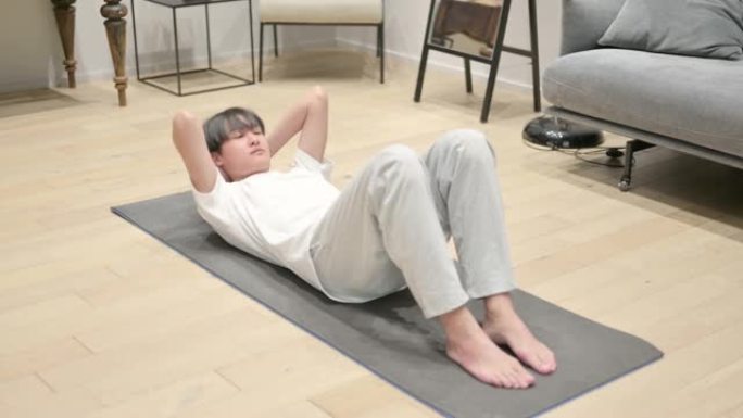 年轻的亚洲男子在家在瑜伽垫上锻炼