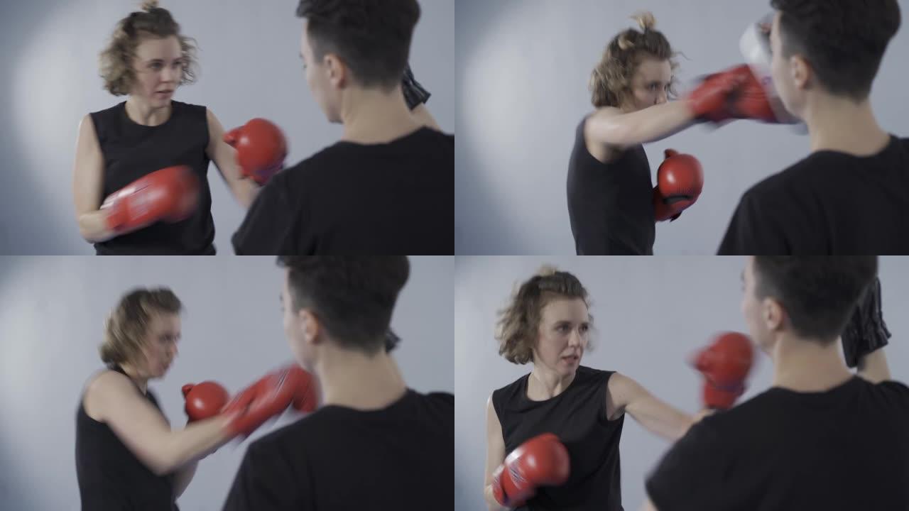 怀抱拳击爪子的女人向新手女战士传授打击技巧。拳击教练手套，MMA，泰拳和合作伙伴联系体育运动员。个人