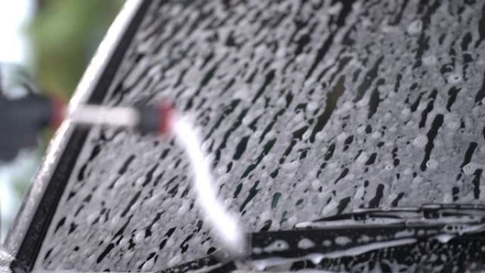 用于消失和清洁的白色泡沫在车身周围流动。概念喷射喷涂机流动清洁产品的化学雪泡沫洗车。