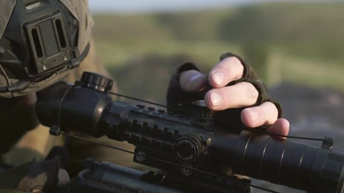 一个戴着绿色防护手套的男子狙击手调整狙击步枪的视线。严肃的人瞄准射击。特写镜头。军事概念