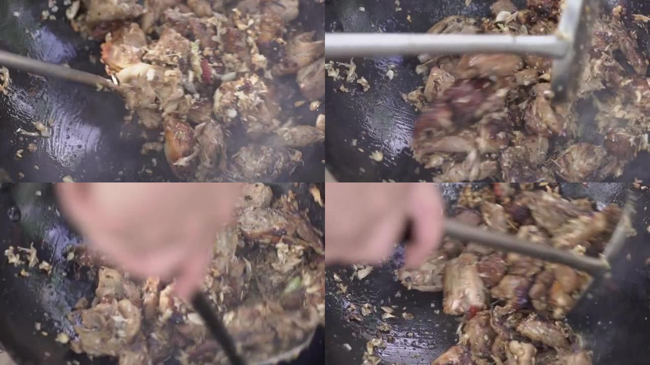 在炉子上的炒锅中用大蒜和黑胡椒炒鸭肉，用不锈钢刮刀在炒锅中用大蒜煮鸭肉