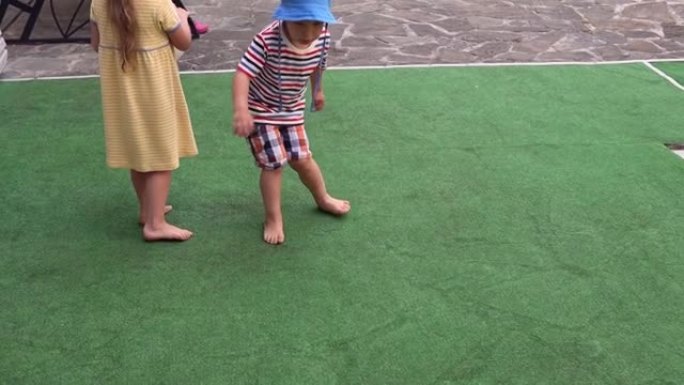 快乐可爱的学龄前儿童男孩和女孩在炎热的夏天玩彩色球。孩子们在院子里玩耍。阳光明媚的户外花园中的婴儿。