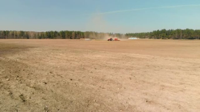 带播种机的拖拉机正在春季农田上积聚灰尘