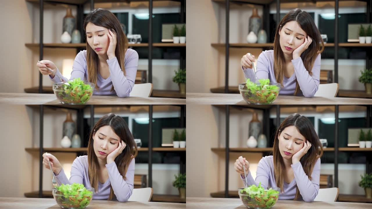 无聊的亚洲女人不喜欢吃蔬菜沙拉