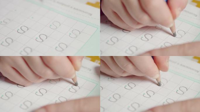 女孩的手学习字母在学校的书上写字母S
