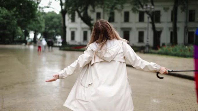 开朗的女人脱下雨伞享受城市中的雨水