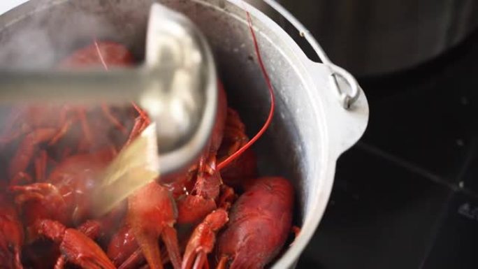 在锅里蒸龙虾海鲜。煮沸的红色小龙虾在平底锅中蒸煮，厨师为您提供豪华的海鲜菜肴，并搭配来自laddle