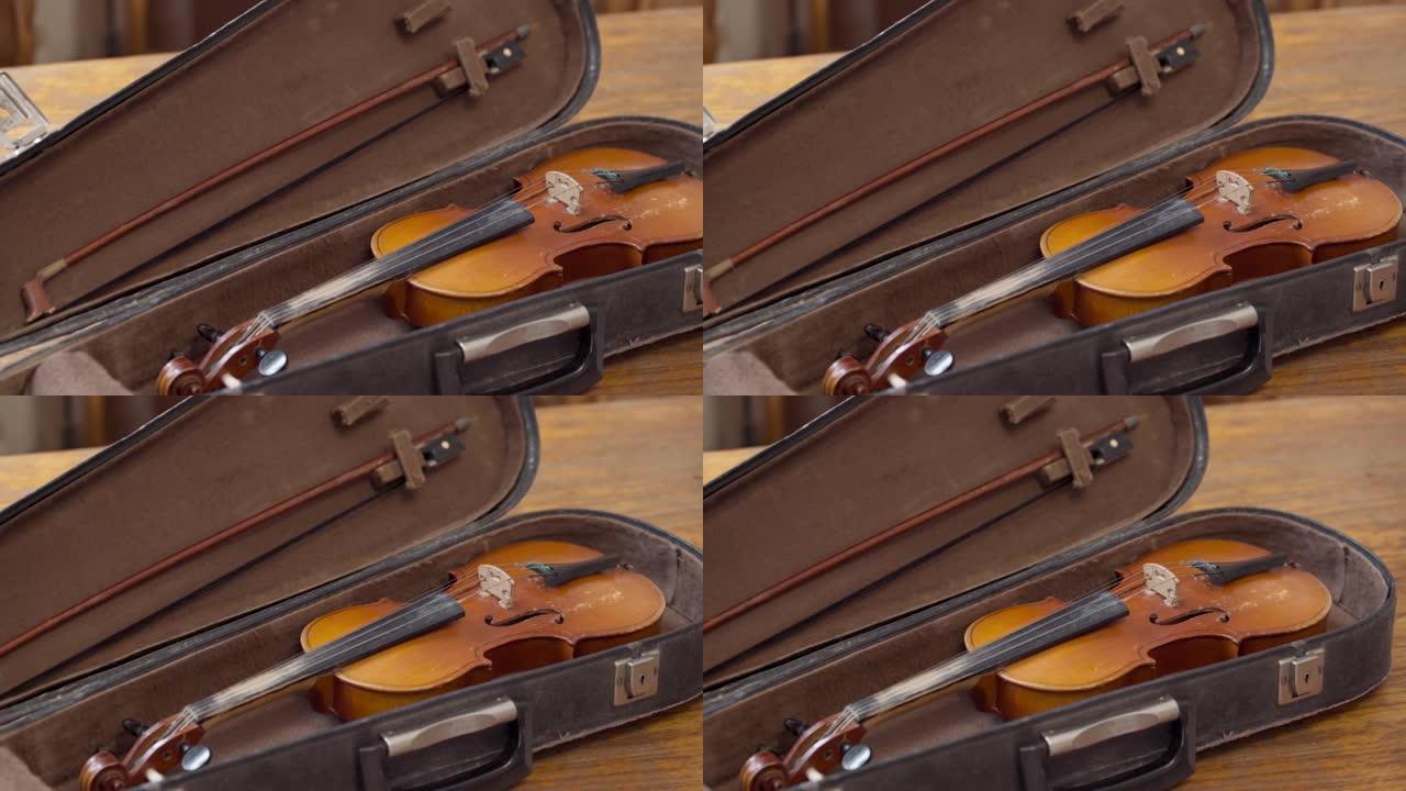 拍摄旧的复古小提琴和弓在一个开放的箱子，箱子，用于存放。从左向右移动。音乐情绪。