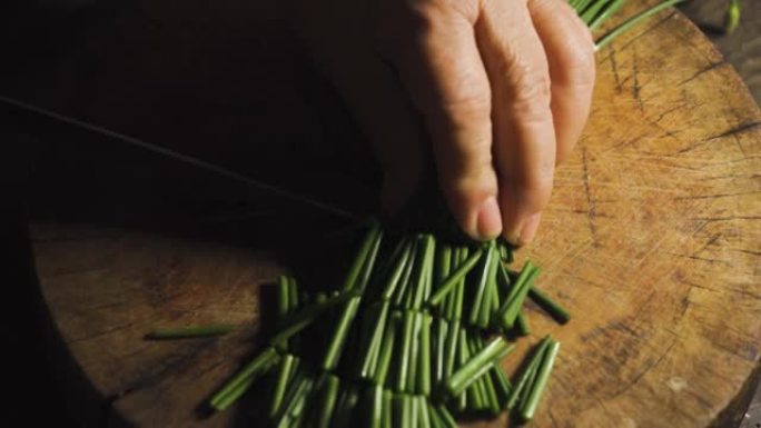 用刀切韭葱的亚洲老太太。准备烹饪食物菜单。亚洲食物。泰国菜。素食。