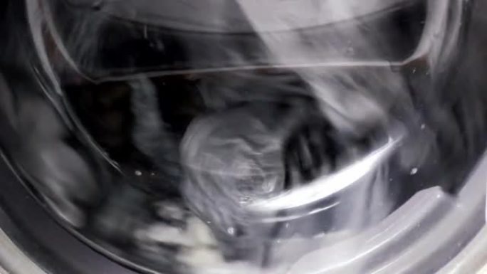 快速旋转洗衣机滚筒在家洗衣时用水旋转脏衣服的特写视图