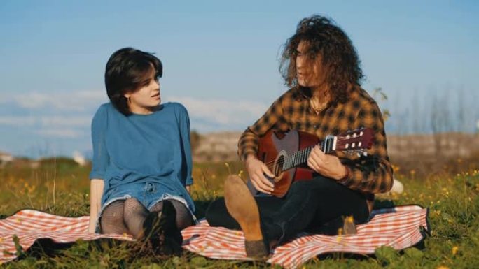 公园里的乐趣 -- 坐在草坪上的年轻夫妇唱歌弹吉他