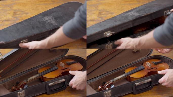 小提琴手用一把老式复古小提琴打开一个箱子。音乐情绪。