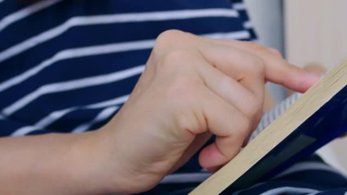 从侧面拍摄的视频，一个女人在看书。手指沿着书中的线条引导，以便更专心地阅读本书。家庭教育