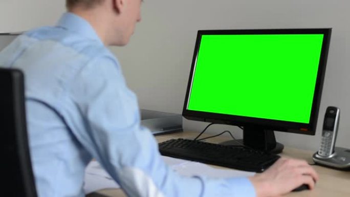 男人在办公室的台式计算机上工作-使用鼠标-绿色屏幕