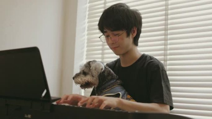 年轻的亚洲青少年在客厅和他的宠物练习电子琴-股票视频
