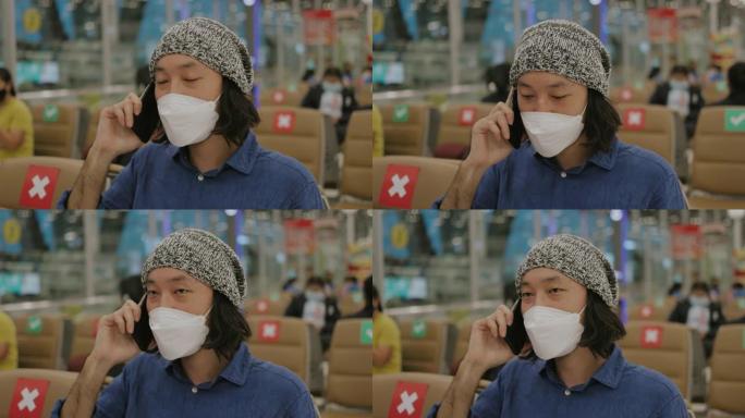 千禧一代亚洲男子，戴着防护口罩，与概念社交疏远，在病毒流行期间用手机交谈-股票视频