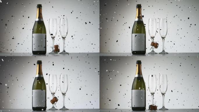 五彩纸屑落在香槟瓶和两个灰色背景下的香槟杯上