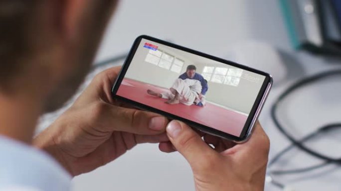 男性医生在智能手机上观看柔道比赛的合成
