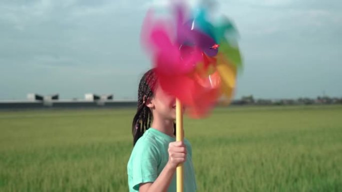 带风车的亚洲小女孩，夏日的小女孩手拿风车，快乐的孩子在户外玩耍