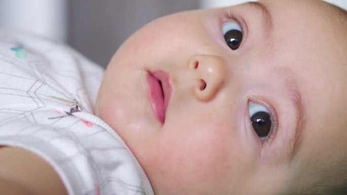 相机特写镜头中婴儿的样子。一个可爱的小宝宝正对着镜头看。照顾孩子的理念，父母的爱。