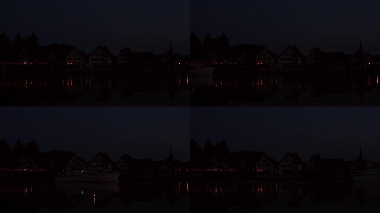 瑞士莱茵河畔的夜堤。一艘有游客的白色游艇正沿着莱茵河航行。