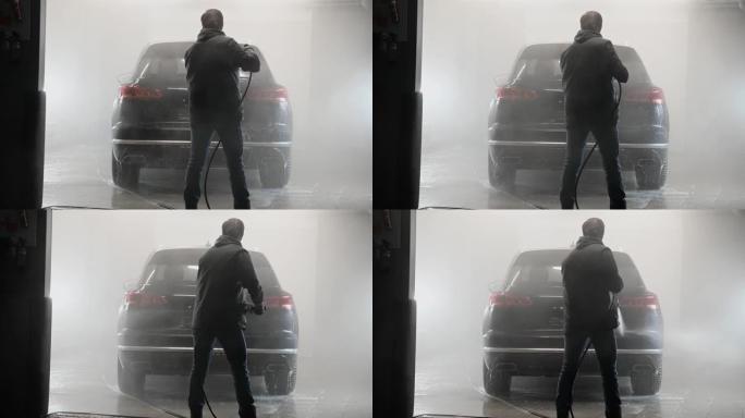 男子从高压清洗机喷水在汽车护理店洗车