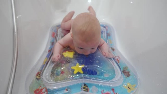 可爱的男婴在浴室玩儿童充气水气垫，婴儿活动玩水垫水下世界婴儿气垫垫。