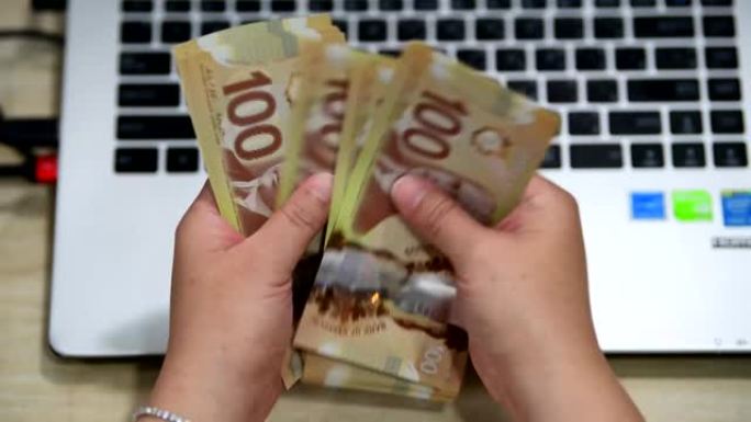 女人从网上企业收到钱后，数着许多加拿大100账单