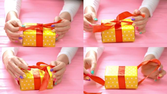 修剪整齐的手在礼品盒上解开丝带。