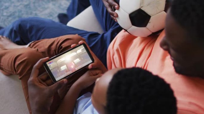 父亲和儿子在家里用智能手机看体育赛事