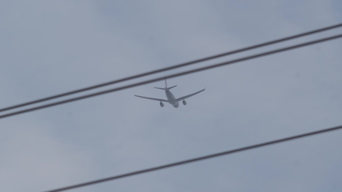 一架飞机从天空飞过飞越电线空隙