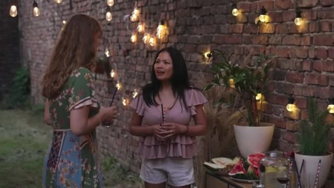 两个女性朋友享受夏季聚会并在后院聊天